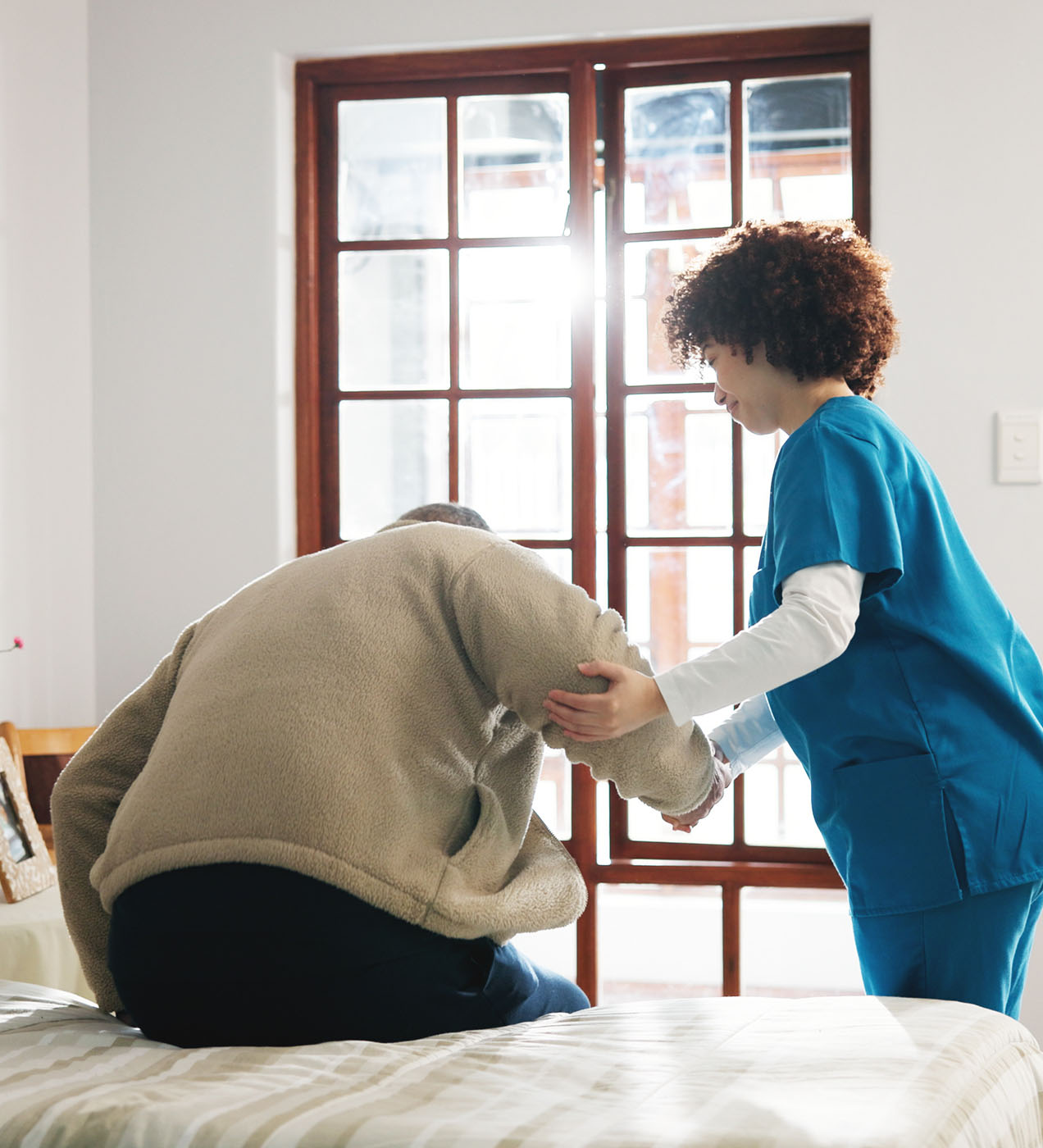 Care worker assisting an elderly person with safe movement and handling in a care home environment